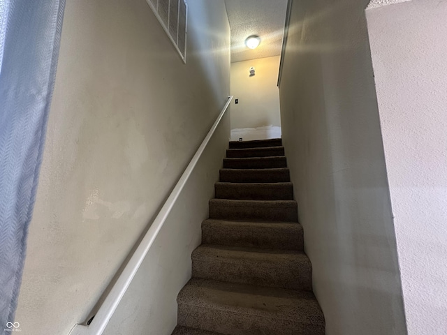 stairway featuring a textured ceiling