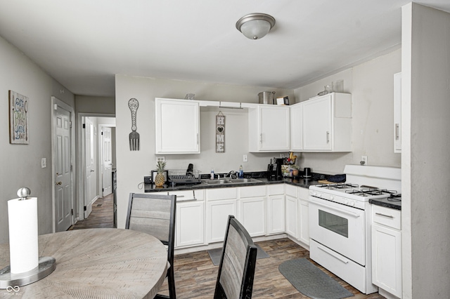 kitchen featuring white gas stove, sink, white cabinets, and dark hardwood / wood-style floors
