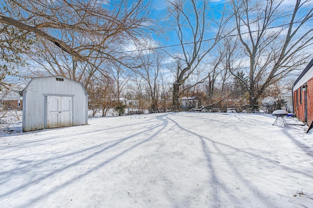 yard layered in snow featuring a storage shed
