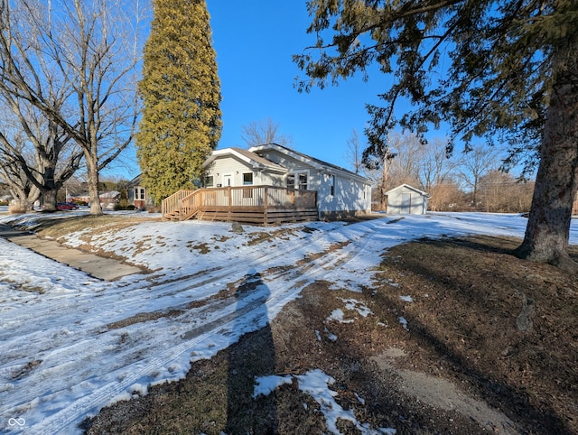 snow covered property with an outdoor structure and a deck