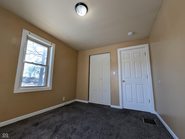 unfurnished bedroom featuring a closet and dark colored carpet