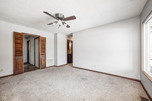 unfurnished bedroom featuring dark carpet, a textured ceiling, and ceiling fan