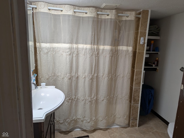 bathroom with tile patterned flooring, vanity, and a textured ceiling