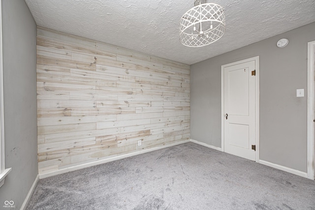 carpeted empty room with a textured ceiling and wood walls