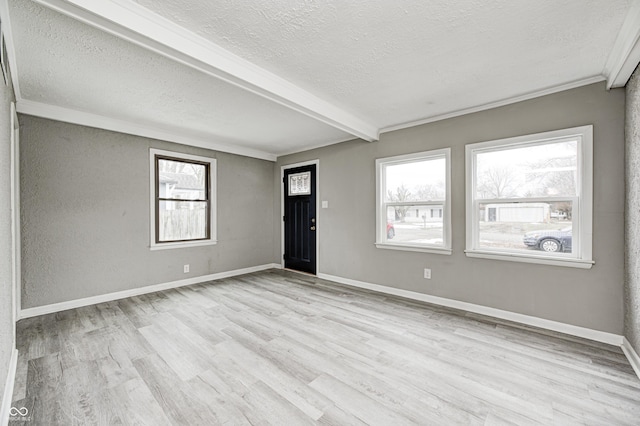 interior space featuring beam ceiling, light hardwood / wood-style floors, a textured ceiling, and a wealth of natural light