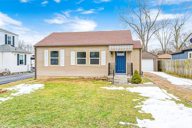 bungalow featuring a garage, an outbuilding, and a front yard