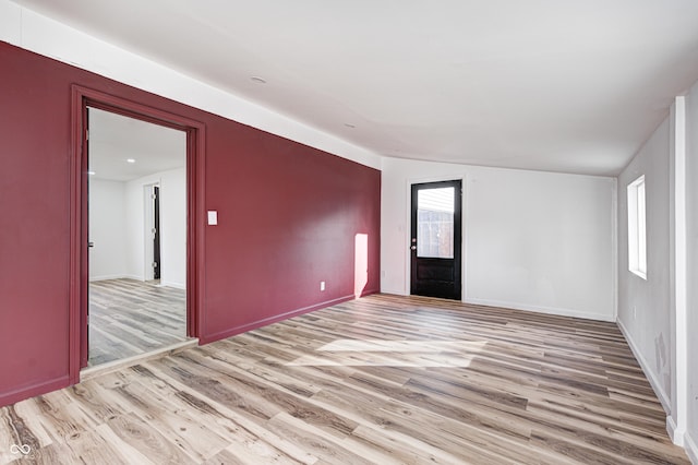 empty room with vaulted ceiling and light hardwood / wood-style floors