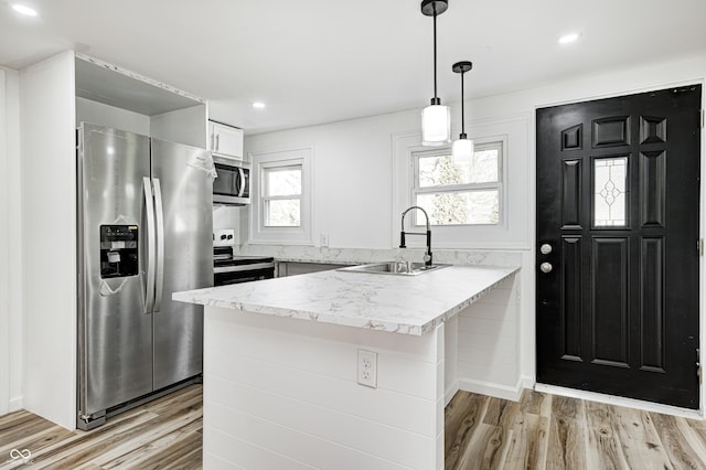 kitchen featuring sink, white cabinets, hanging light fixtures, kitchen peninsula, and stainless steel appliances