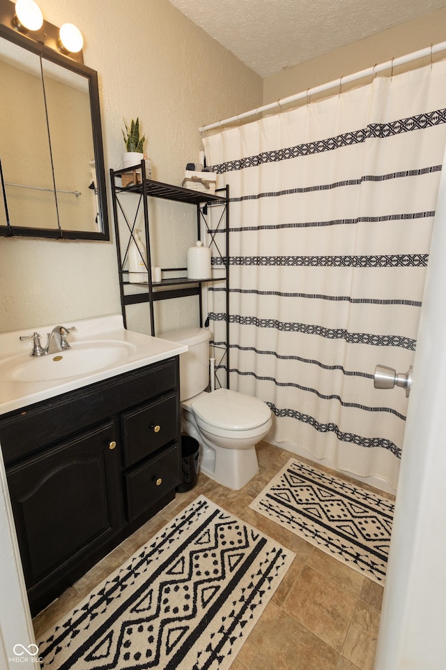 bathroom with vanity, toilet, and a textured ceiling