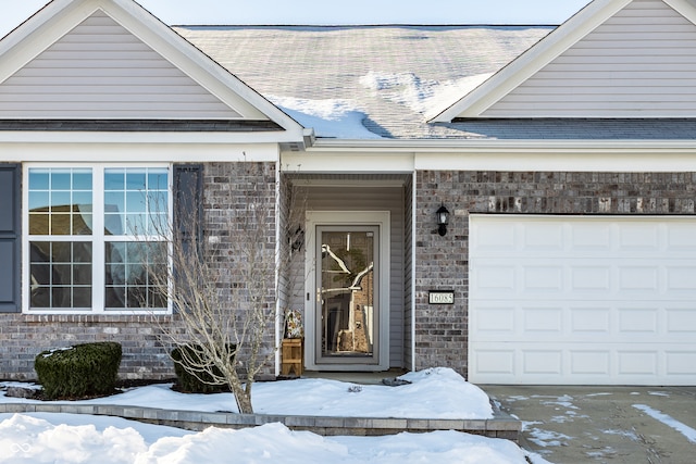 snow covered property entrance with a garage