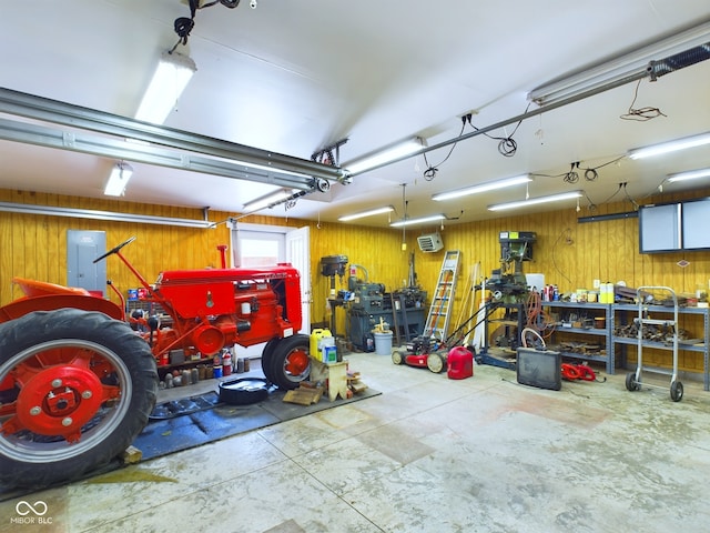 garage featuring wood walls, electric panel, and a workshop area