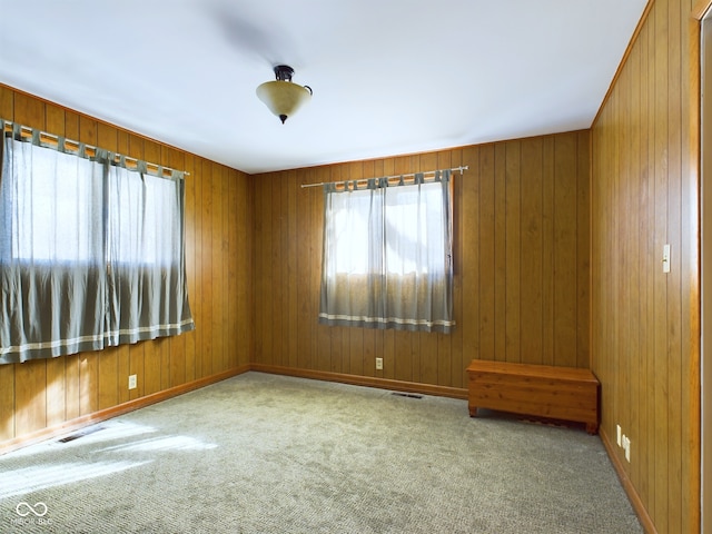 carpeted spare room with wood walls