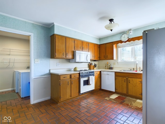 kitchen with ornamental molding, washer and clothes dryer, sink, and white appliances