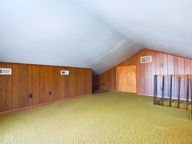 additional living space featuring wooden walls, carpet flooring, and vaulted ceiling