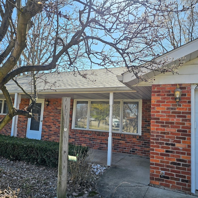 view of home's exterior with brick siding and a shingled roof