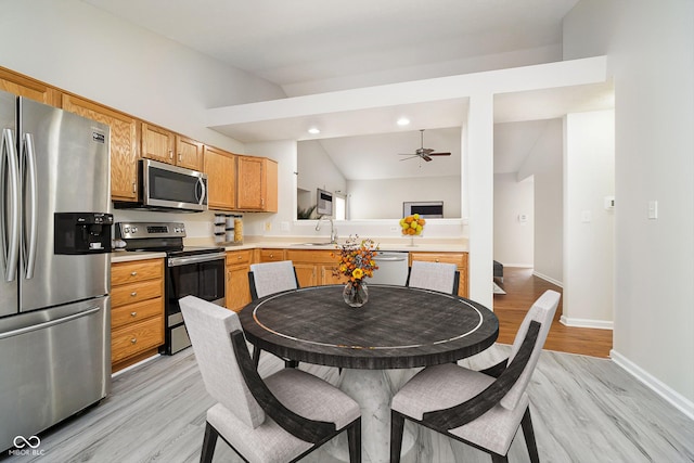 kitchen featuring baseboards, lofted ceiling, appliances with stainless steel finishes, light countertops, and a sink