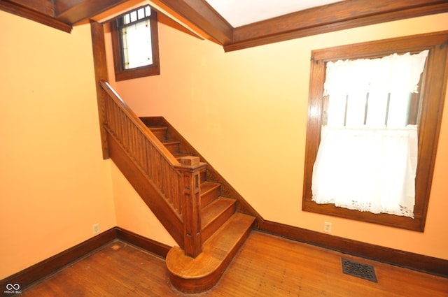 staircase with crown molding and hardwood / wood-style floors