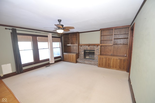 unfurnished living room with crown molding, light carpet, ceiling fan, and a fireplace