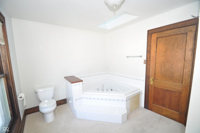 bathroom with tiled tub, toilet, and a skylight