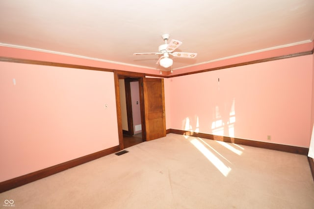 empty room with carpet floors, ornamental molding, and ceiling fan