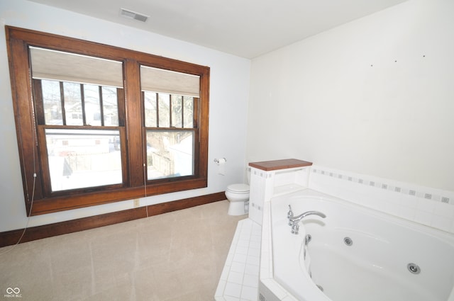 bathroom featuring tile patterned floors, toilet, and tiled tub