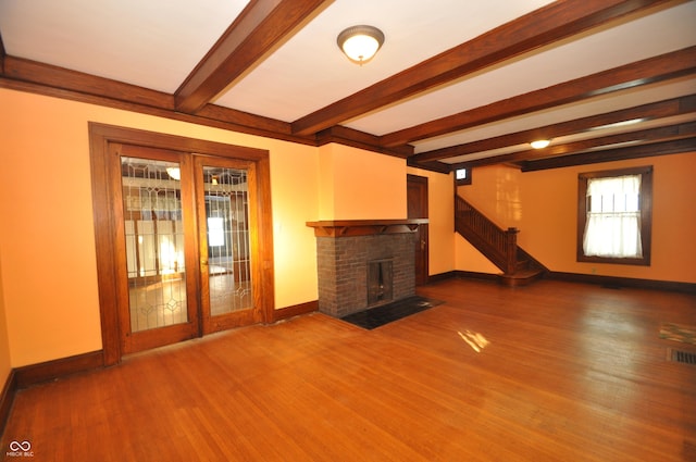 unfurnished living room featuring beamed ceiling, wood-type flooring, and a fireplace