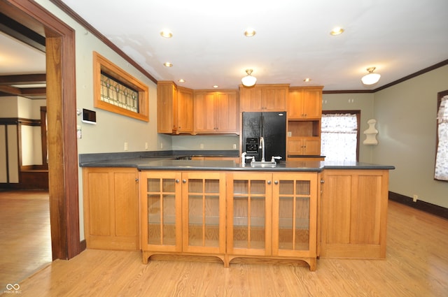 kitchen featuring light wood-type flooring, ornamental molding, and black fridge