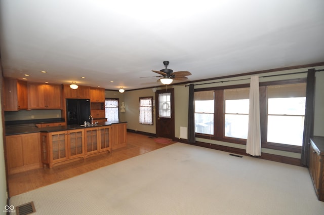 kitchen with black fridge, sink, ceiling fan, and light hardwood / wood-style floors