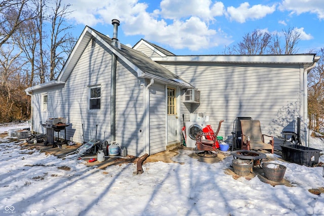 snow covered back of property with washing machine and dryer and an outdoor fire pit