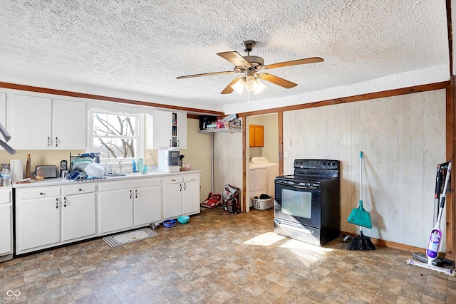 kitchen with ceiling fan, white cabinetry, electric range, washing machine and dryer, and a wood stove