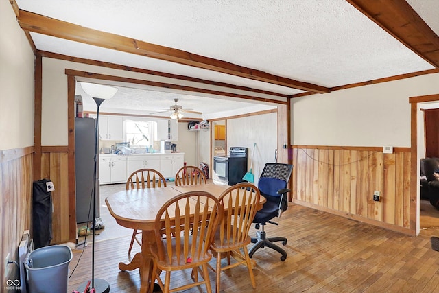 dining area featuring wooden walls, light hardwood / wood-style floors, and a textured ceiling