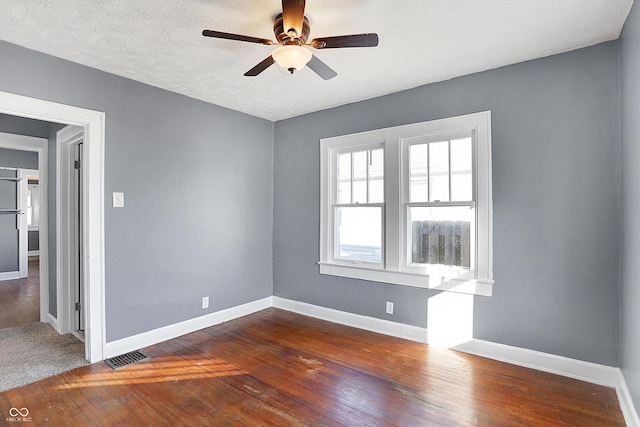 empty room with ceiling fan, dark hardwood / wood-style floors, and a textured ceiling