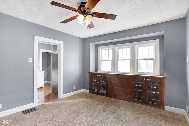 carpeted empty room featuring ceiling fan and a textured ceiling