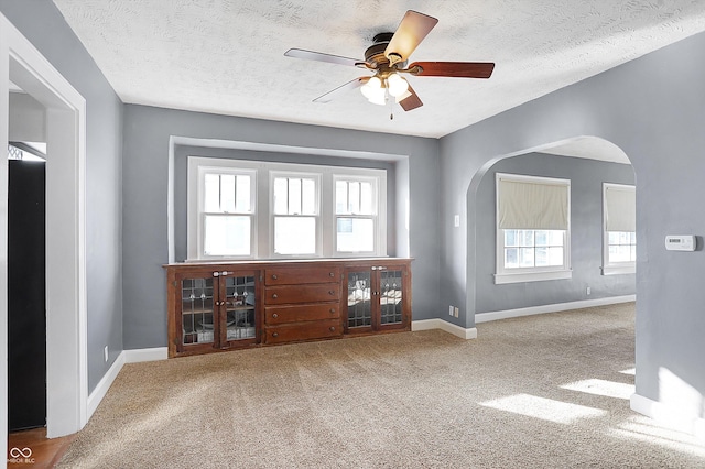 carpeted spare room with ceiling fan, a healthy amount of sunlight, and a textured ceiling