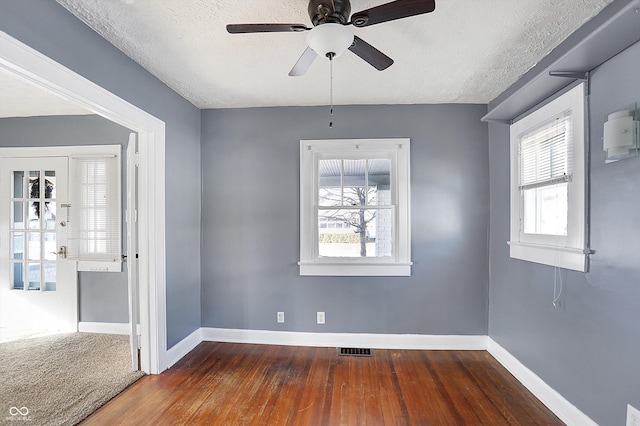 spare room with dark hardwood / wood-style flooring, a textured ceiling, and a healthy amount of sunlight