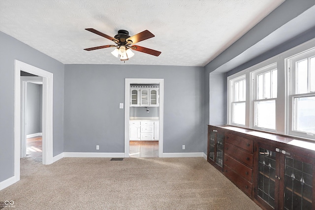 carpeted empty room featuring ceiling fan and a textured ceiling