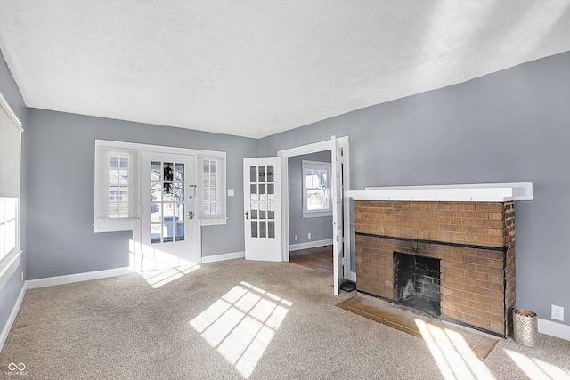 unfurnished living room with a brick fireplace, light carpet, and a textured ceiling