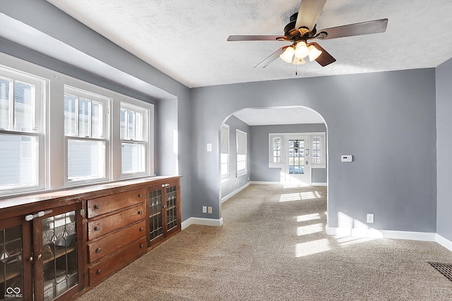 unfurnished room featuring ceiling fan, light colored carpet, and a textured ceiling