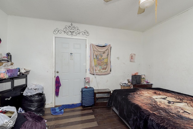 bedroom with dark wood-type flooring, a textured ceiling, and ceiling fan