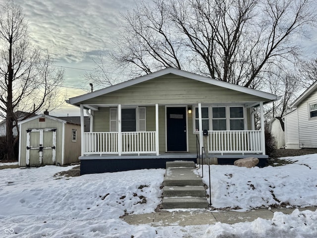 bungalow-style home with a porch and a storage shed