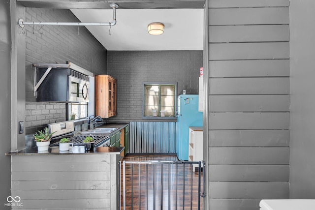 interior space with sink, stainless steel range, wooden walls, and fridge