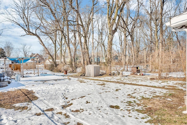 snowy yard featuring a storage shed