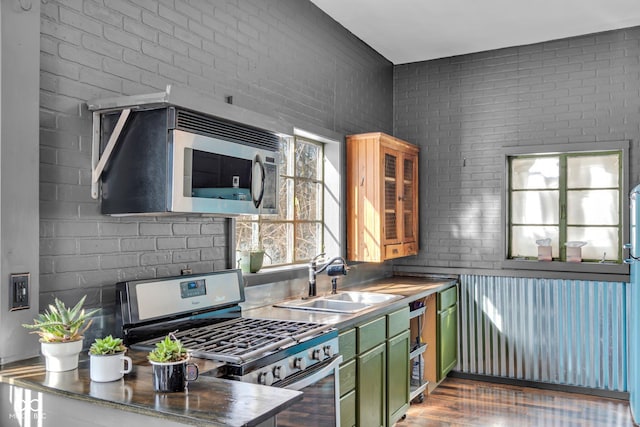 kitchen with brick wall, appliances with stainless steel finishes, sink, and green cabinetry