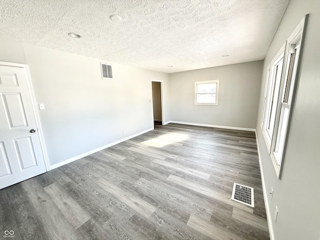 empty room featuring dark hardwood / wood-style floors and a textured ceiling