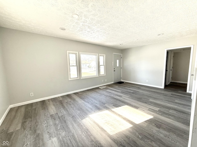 spare room featuring a textured ceiling and dark hardwood / wood-style flooring