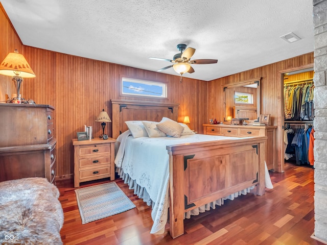 bedroom with multiple windows, a spacious closet, a textured ceiling, and ceiling fan