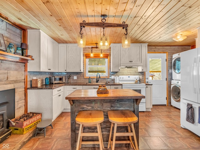 kitchen featuring white cabinetry, stacked washer / drying machine, wood ceiling, and white appliances