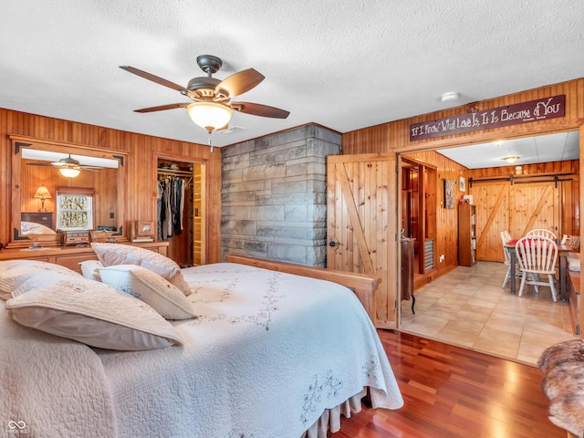 bedroom featuring a textured ceiling, a walk in closet, a barn door, and ceiling fan