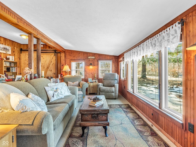 living room with vaulted ceiling, a barn door, a textured ceiling, and wood walls