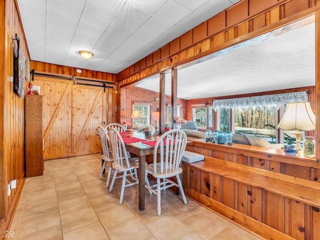 dining area featuring a barn door and wood walls